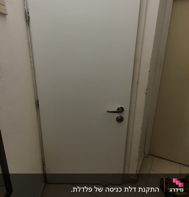 דלת לבנה עם ידית מתכת וחלקי מתכת על הרצפה